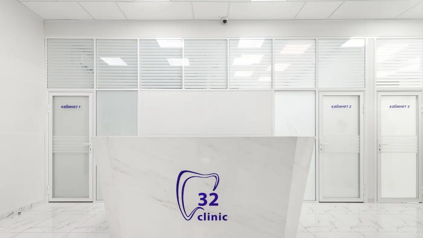 Стойка администратора с логотипом 32 Clinic и дверями кабинетов приёма